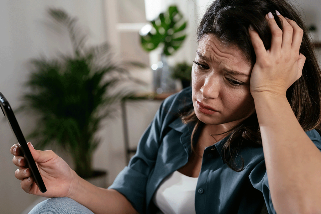 A woman looks upset as she turns away from her phone. She is struggling with a fentanyl addiction.