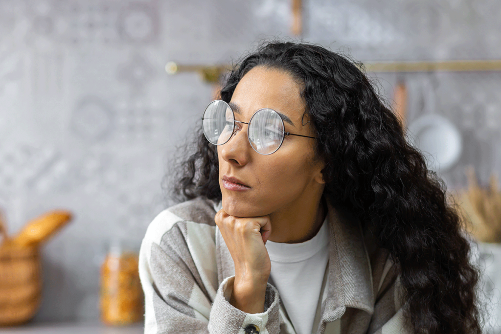 a woman with glasses looks off to the distance wondering the signs of inattentive adhd