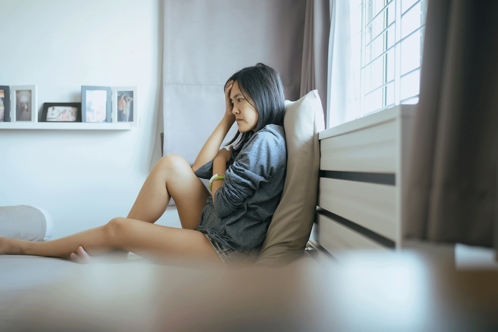 A woman sits on the floor and experiences the signs of depression.