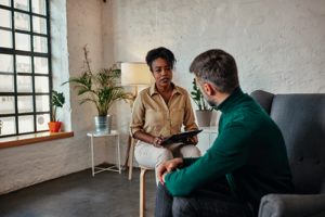 A man gets treatment for bipolar disorder symptoms while sitting with a therapist.